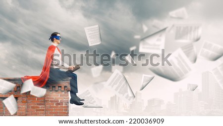 Young man in superhero costume reading book