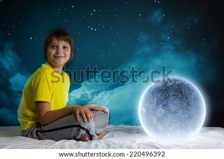Cute boy sitting in bed and dreaming about moon