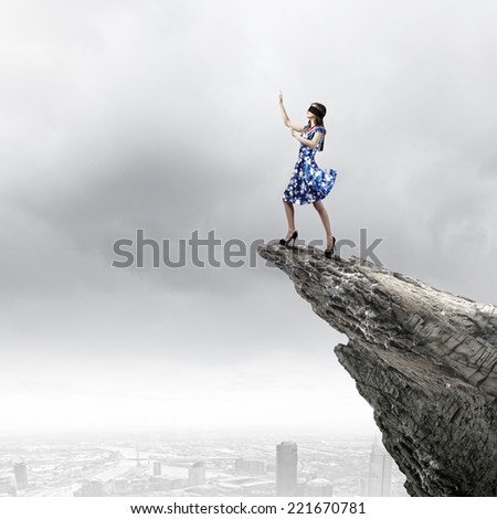 Young woman in blue dress standing on mountain edge