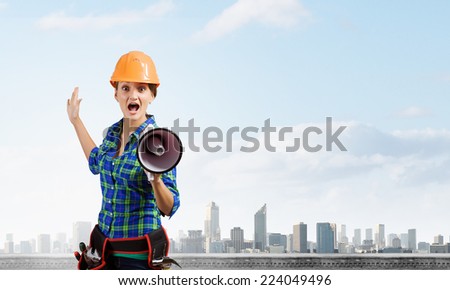Young woman builder in hardhat screaming in megaphone