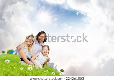 Happy family of mother father and daughter sitting on grass