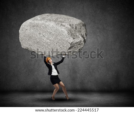 Young woman engineer lifting huge stone above head