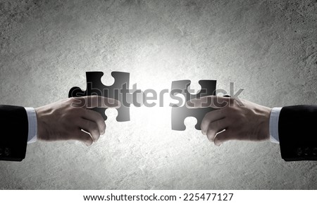 Close up of human hands connecting puzzle elements