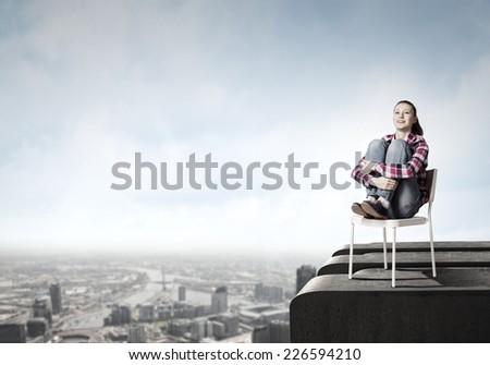 Young woman in casual sitting on in chair on top of building