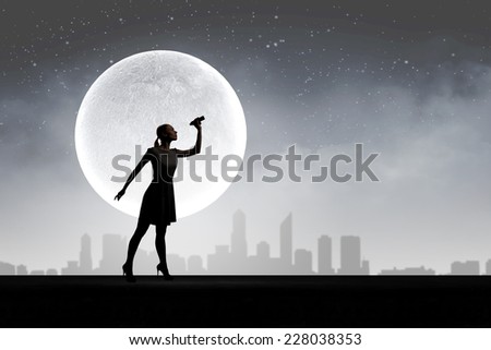 Silhouette of woman at night looking in binoculars