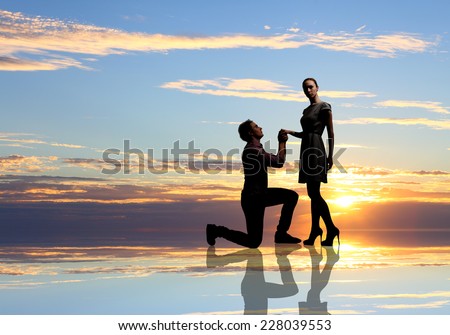 Young man standing on knees and proposing a woman