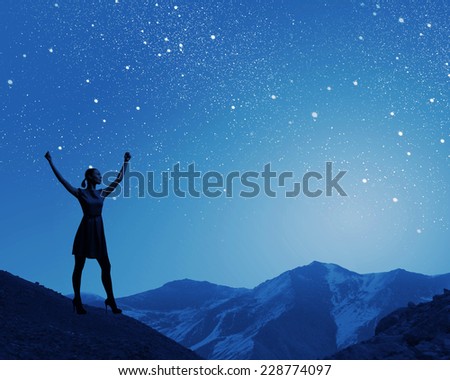 Silhouette of woman in dress at night with hands up