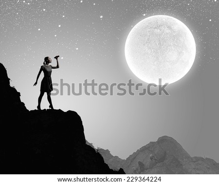 Silhouette of woman at night looking in binoculars