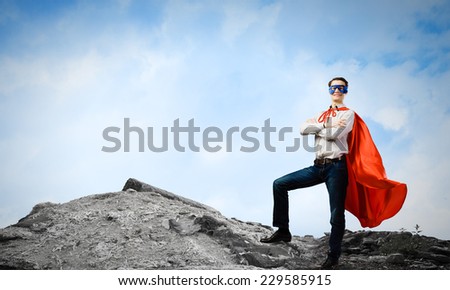 Confident superman in cape and mask standing on ruins