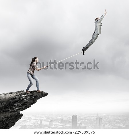 Woman holding on rope businessman trying to escape