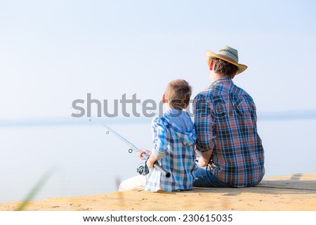 boy and his father fishing together from a pier