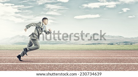 Young businessman in suit running on stadium track
