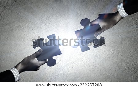Close up of human hands connecting puzzle elements