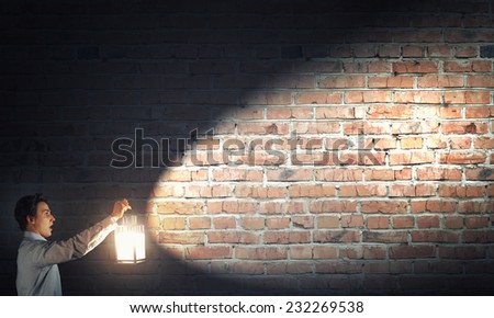 Young handsome businessman walking in darkness with lantern