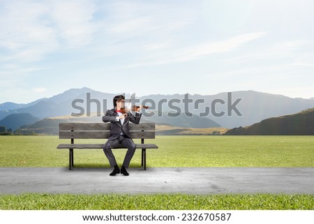 Young man in suit sitting on bench and playing violin