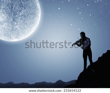 Young man playing violin at night under moon light