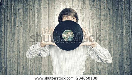 Young handsome man dj holding disco plate Elements of this image furnished by NASA