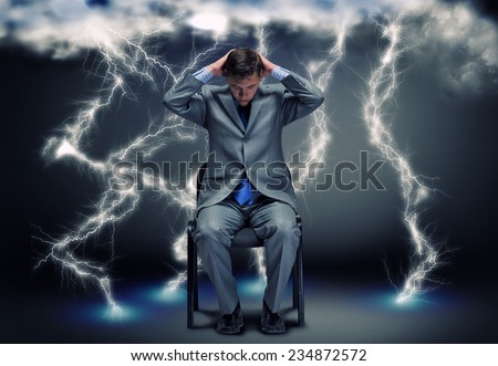 Conceptual image of troubled businessman sitting under rain