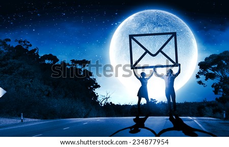 Silhouettes of young couple at night holding email sign