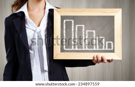 Young woman holding frame with decreasing graph