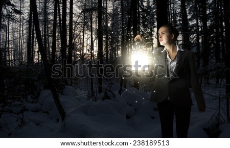 Young pretty businesswoman with lantern in darkness