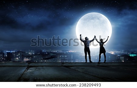 Silhouettes of young romantic couple standing under the moon light