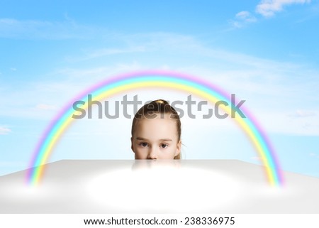 Little cute girl looking at colorful rainbow