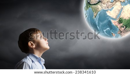Little boy of school age looking at Earth planet. Elements of this image are furnished by NASA