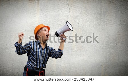 Young emotional woman builder screaming in megaphone