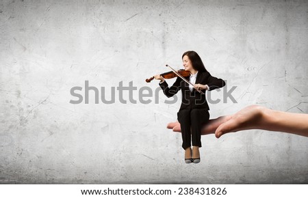 Young woman sitting in palm and playing violin