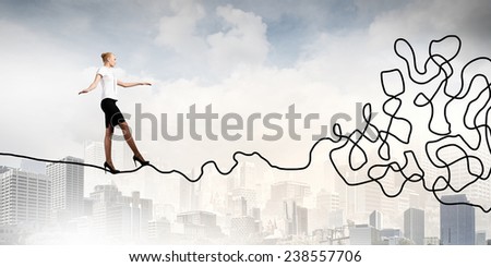 Young businesswoman walking on twisted rope high in sky