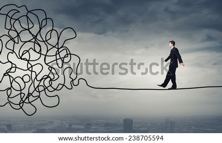 Businessman walking on twisted rope high in sky