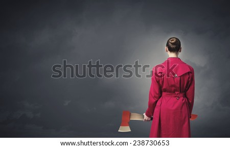 Rear view of woman in red coat with axe in hands