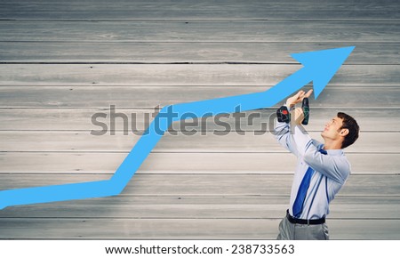 Young businessman using drill to fix growing arrow