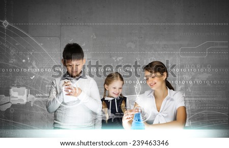 Young teacher and her pupils doing tests at chemistry lesson