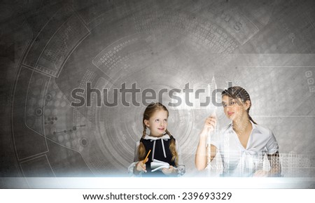 Young teacher and her pupil at lesson looking at media screen