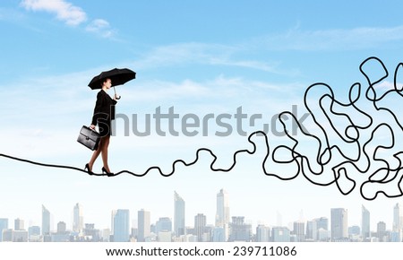 Young businesswoman walking on twisted rope high in sky
