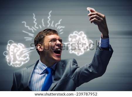 Angry businessman screaming furiously in mobile phone