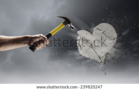 Close up of hammer in human hand breaking stone heart