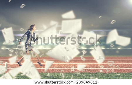 Young businesswoman in suit running on stadium track