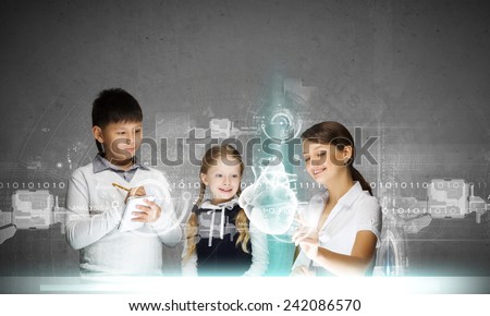 Young teacher and her pupils examining hologram of human heart