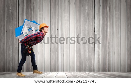 Young smiling craftsman carrying house model on back