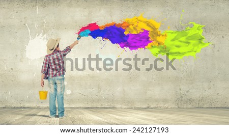 Boy of school age painting wall with brush