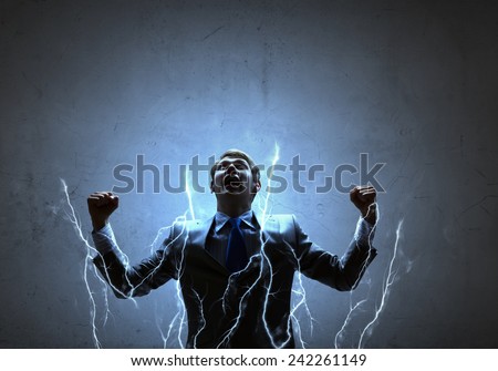 Young powerful businessman n lightning flashes with hands up