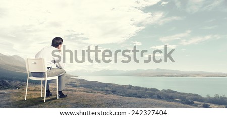 Back view of businessman sitting in chair and thinking