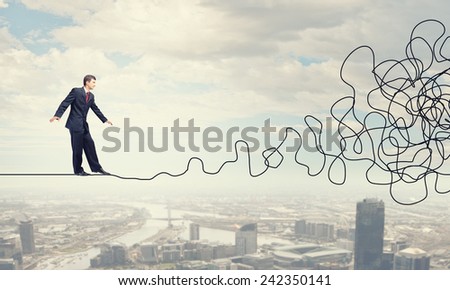 Businessman walking on twisted rope high in sky