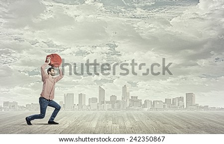 Young man in casual carrying heavy red bag