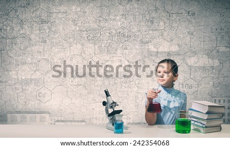 Cute girl at chemistry lesson making tests
