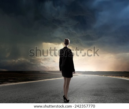 Back view of businesswoman standing on road and looking far away