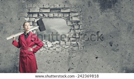 Rear view of woman in red coat with hammer in hands